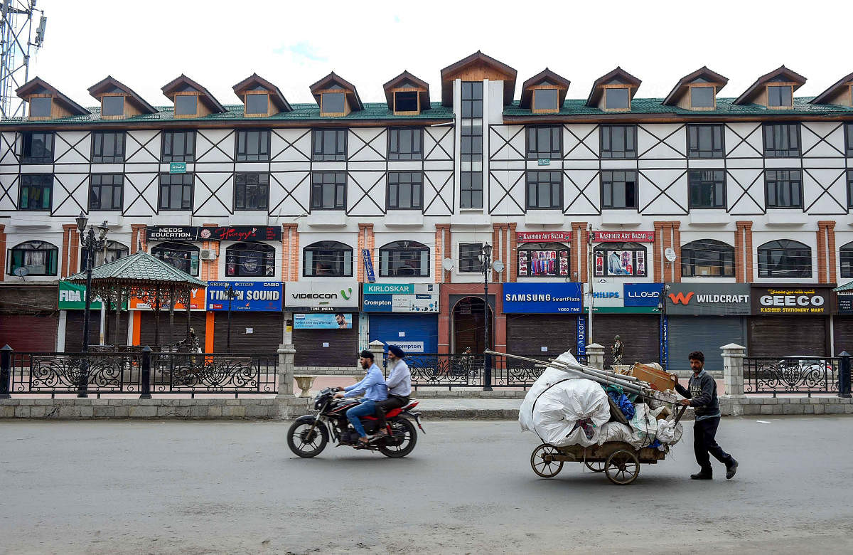 A man pushes his cart through a deserted Lal Chowk area in Srinagar. PTI photo