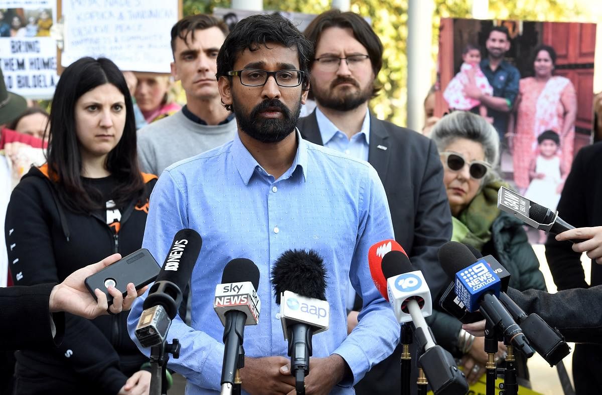 Tamil Refugee Council spokesperson Aran Mylvaganam (C) speaks to the media as protesters hold up placards and photos outside the Federal Court in Melbourne on August 30, 2019. Photo/ AFP