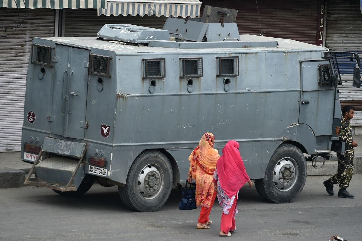 Indian Kashmiri residents walks past a paramilitary armoured vehicle at a roadblock during a lockdown in Srinagar on August 30, 2019. (Photo by AFP)