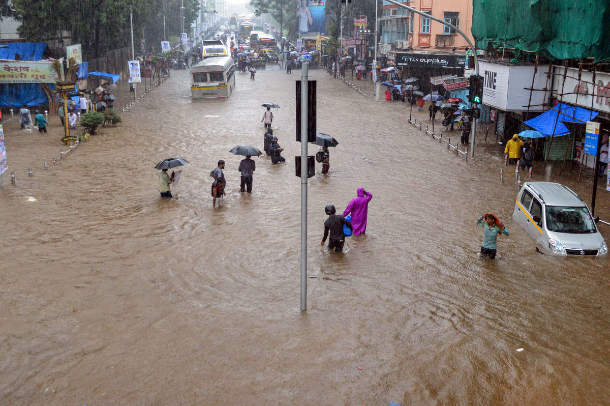 Residents wade through a flooded street, following heavy rains in low lying area of Dadar, in Mumbai. (PTI Photo)