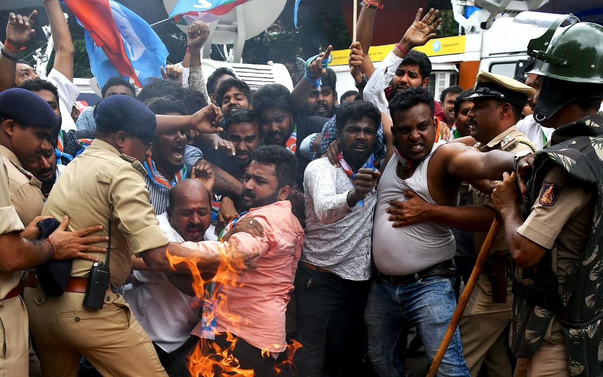 Members of the Karnataka Congress scuffle with police as they burn tyres and shout slogans against Indian Prime Minister Narendra Modi and Home Minister Amit Shah during a protest staged by the party in Bangalore. (AFP Photo)