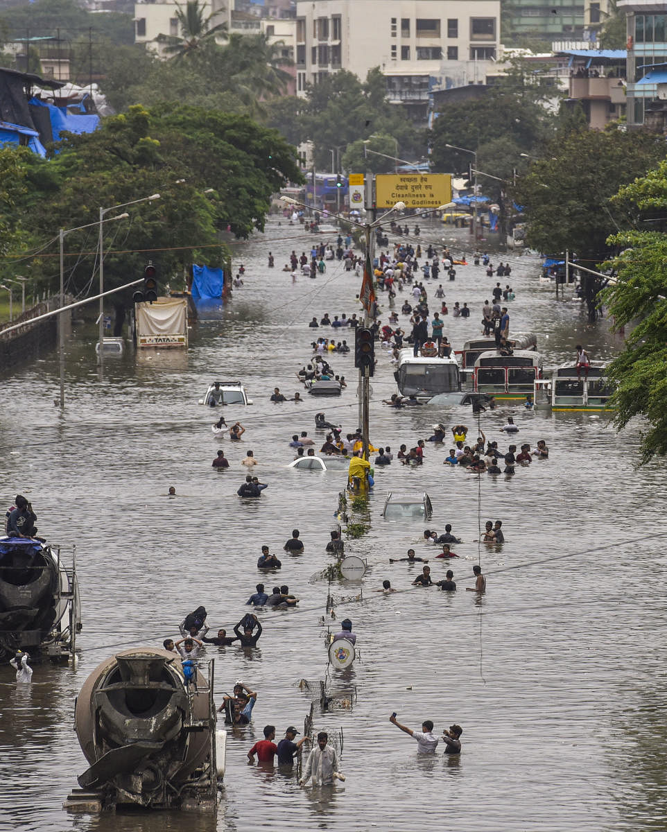 People wade through a flooded railway tracks during heavy rain, in Mumbai. (PTI Photo)