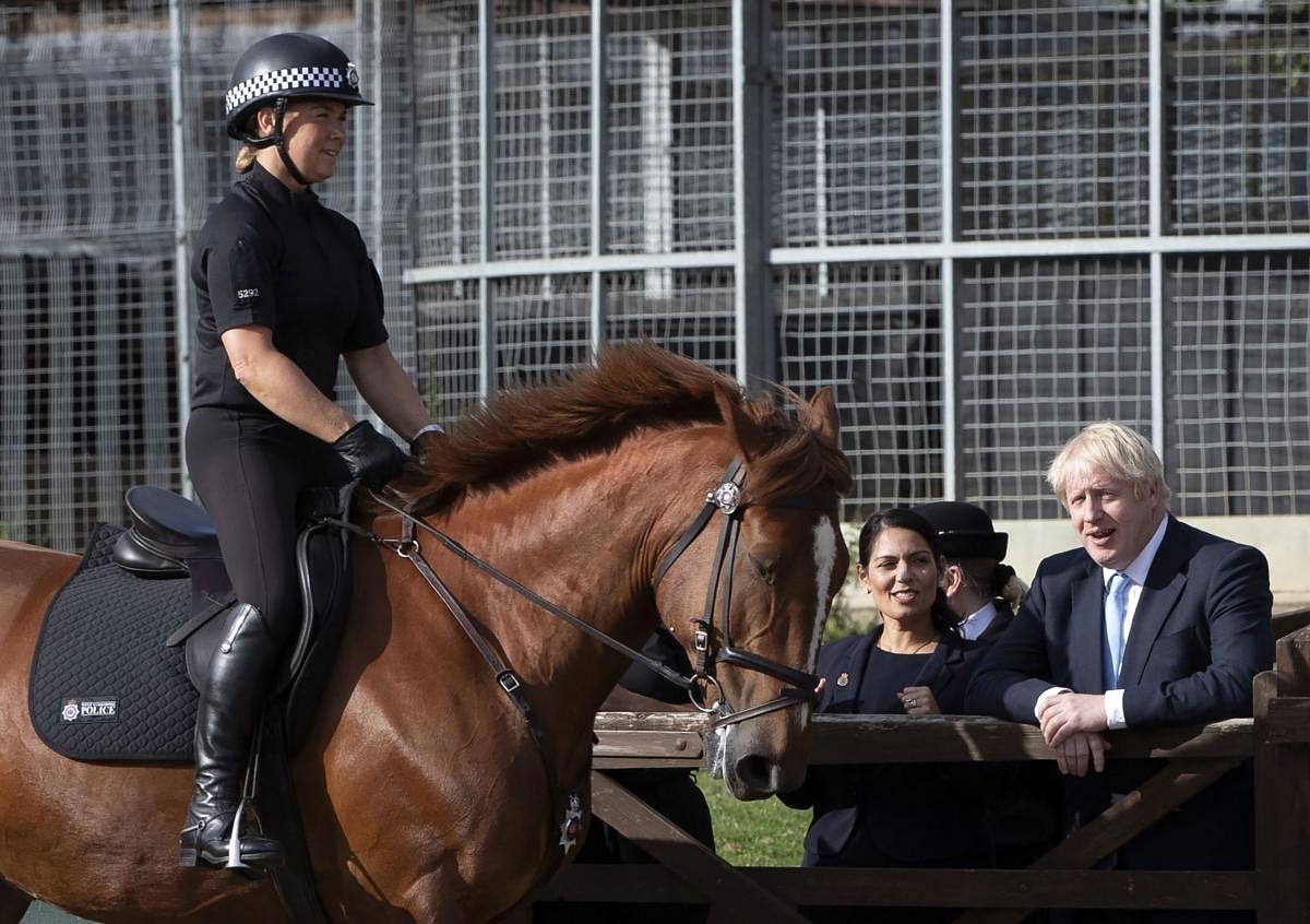 Britain's Prime Minister Boris Johnson (R) and Britain's Home Secretary Priti Patel (2nd R) watch horses exercising at a stables during a visit with the police in Wakefield, West Yorkshire, northern England, on September 5, 2019. (Photo by Danny Lawson /