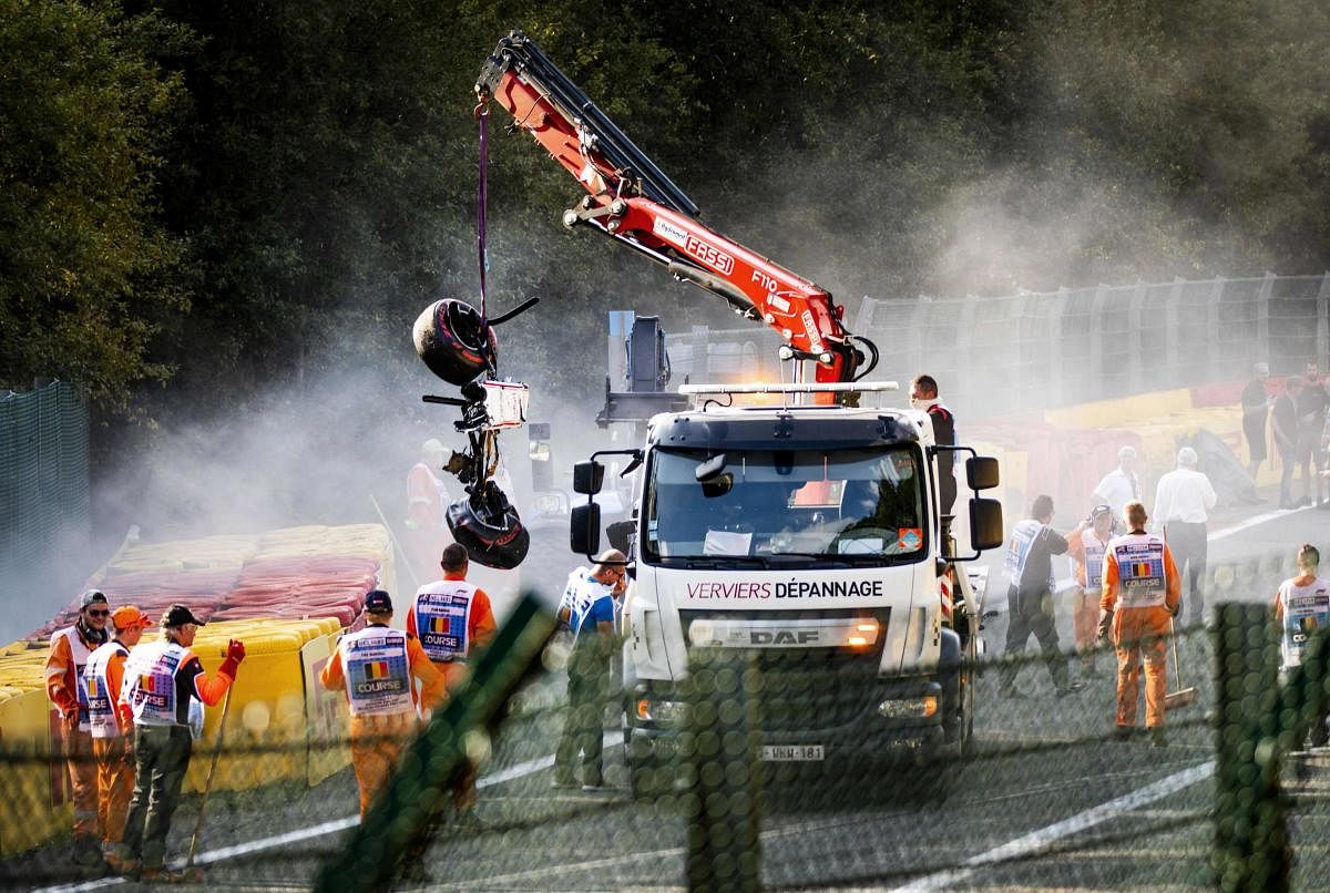 Track marshals look on as a crane lift parts of the damaged car of Sauber's Ecuadorian driver Juan Manuel Correa onto a truck following a serious accident involving several drivers during a Formula 2 race at the Spa-Francorchamps circuit in Spa, Belgium,