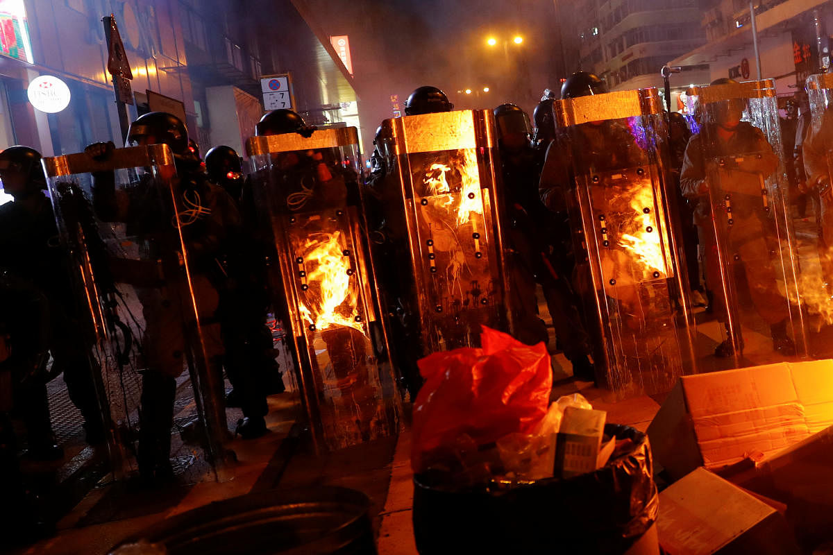 Riot police officers stand behind a burning barricade during a demonstration in Mong Kok district in Hong Kong. (Reuters Photo)