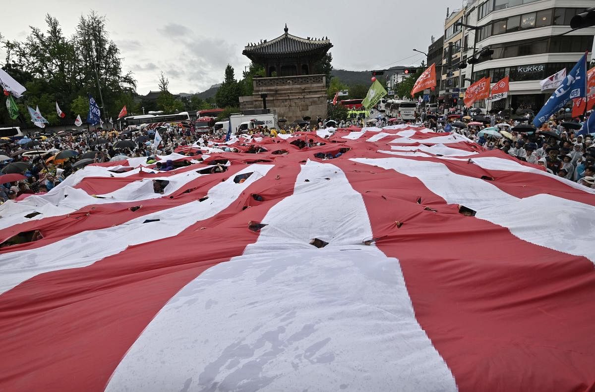 South Korean protesters tear a huge Japanese rising sun flag during an anti-Japanese rally marking the anniversary of Korea's liberation from Japan's. AFP Photo