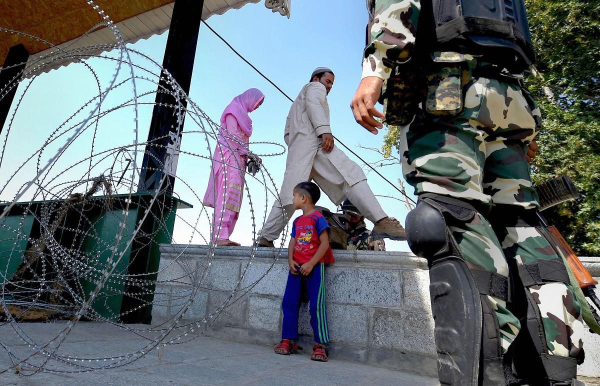 A couple makes way by a barricade of razor wires during curfew-like restrictions in Srinagar, Tuesday, Sept. 10, 2019. (PTI Photo)