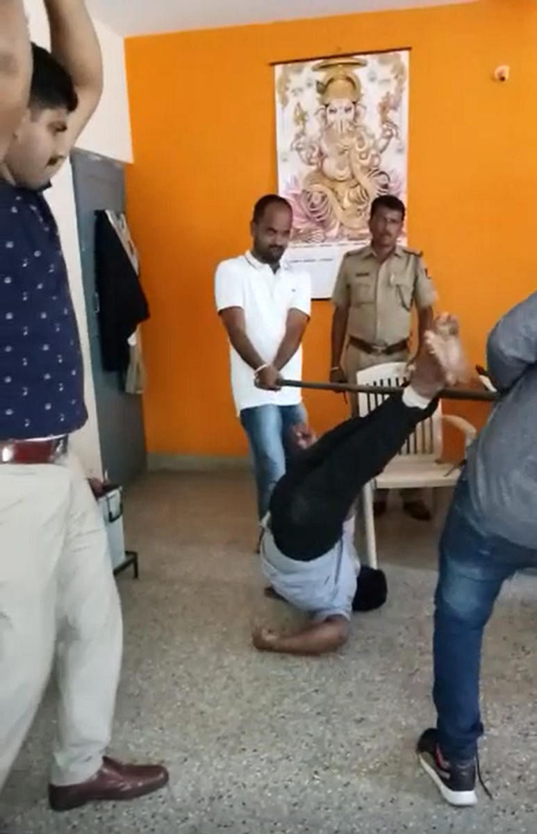 A video grab shows PSI Srikante Gowda (left) thrashingaccused Yeshwanth (inset) with his lathi, even as two constables pin him to the ground.