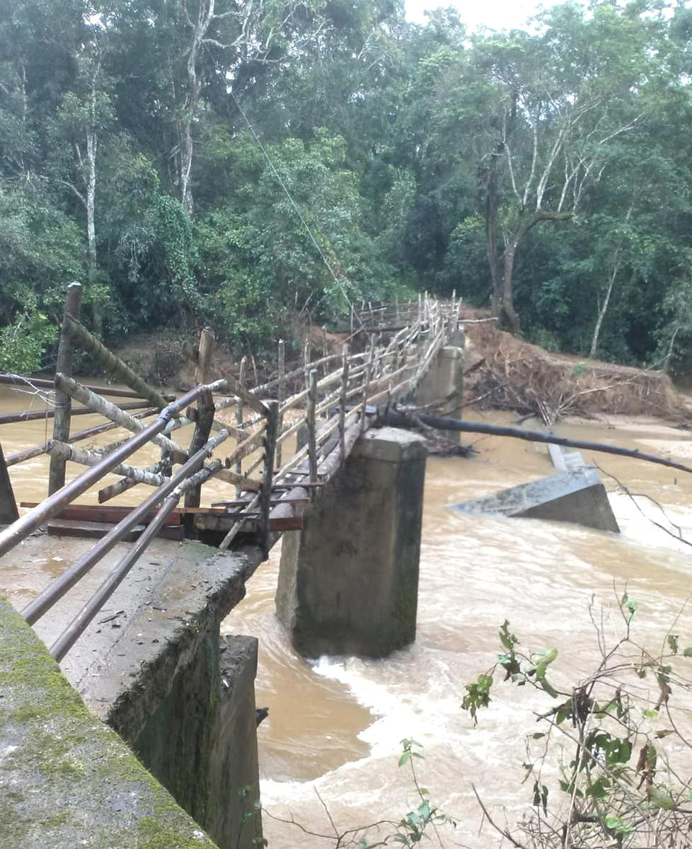 After the collapse of the footbridge in the flood, the villagers have constructed a makeshift temporary bridge using wooden logs at Donisara village in Chikkamagaluru district.
