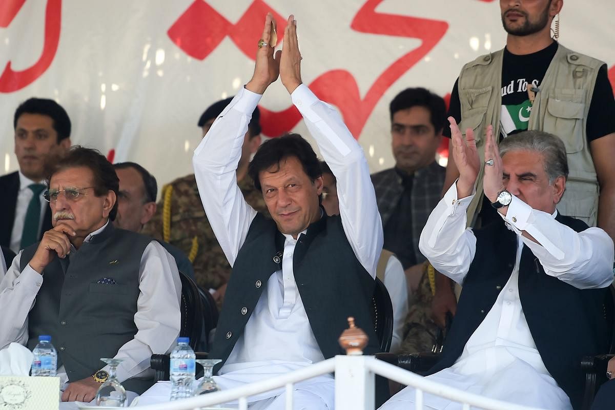 Pakistan's Prime Minister Imran Khan (C) is accompanied by Foreign Minister Shah Mehmood Qureshi (R) and prime minister of Pakistan-administered Kashmir Raja Farooq Haider (L) as he greets the crowd during a rally in Muzaffarabad on September 13, 2019. (Photo by AFP)
