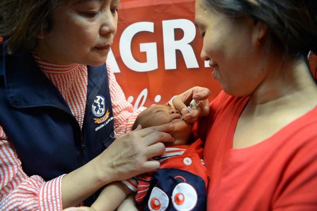 mother watches as a health worker administers a polio vaccine during an anti-polio campaign in Manila. (AFP Photo)