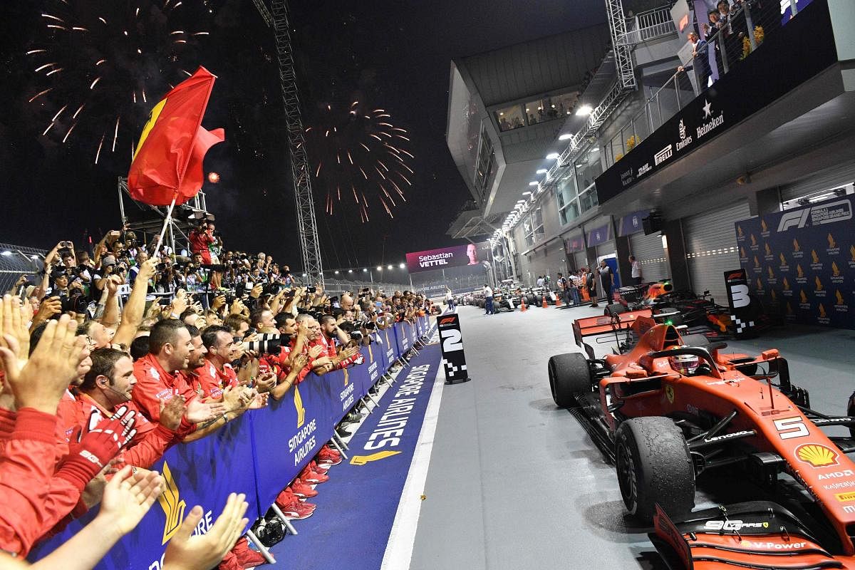 Ferrari team members celebrate as Ferrari's German driver Sebastian Vettel returns to the pit to celebrate his victory at the end of the Formula One Singapore Grand Prix night race at the Marina Bay Street Circuit in Singapore on September 22, 2019. Photo