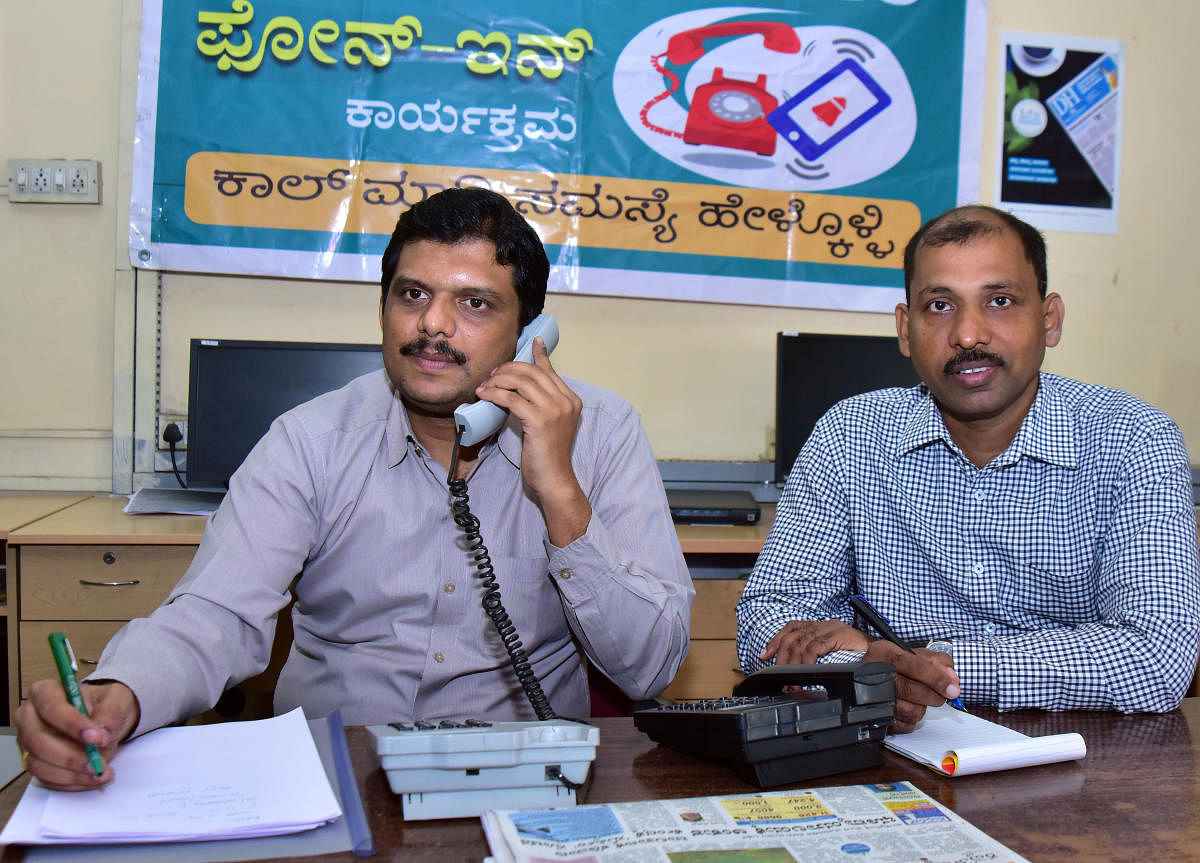 Mangaluru Division Senior Superintendent of Post Offices N Sriharsha receives a call during phone-in programme organised by Prajavani at DH-PV editorial office in Balmatta on Wednesday. Assitant Superintendent of Post Offices Shrinath looks on. DH PHOTO