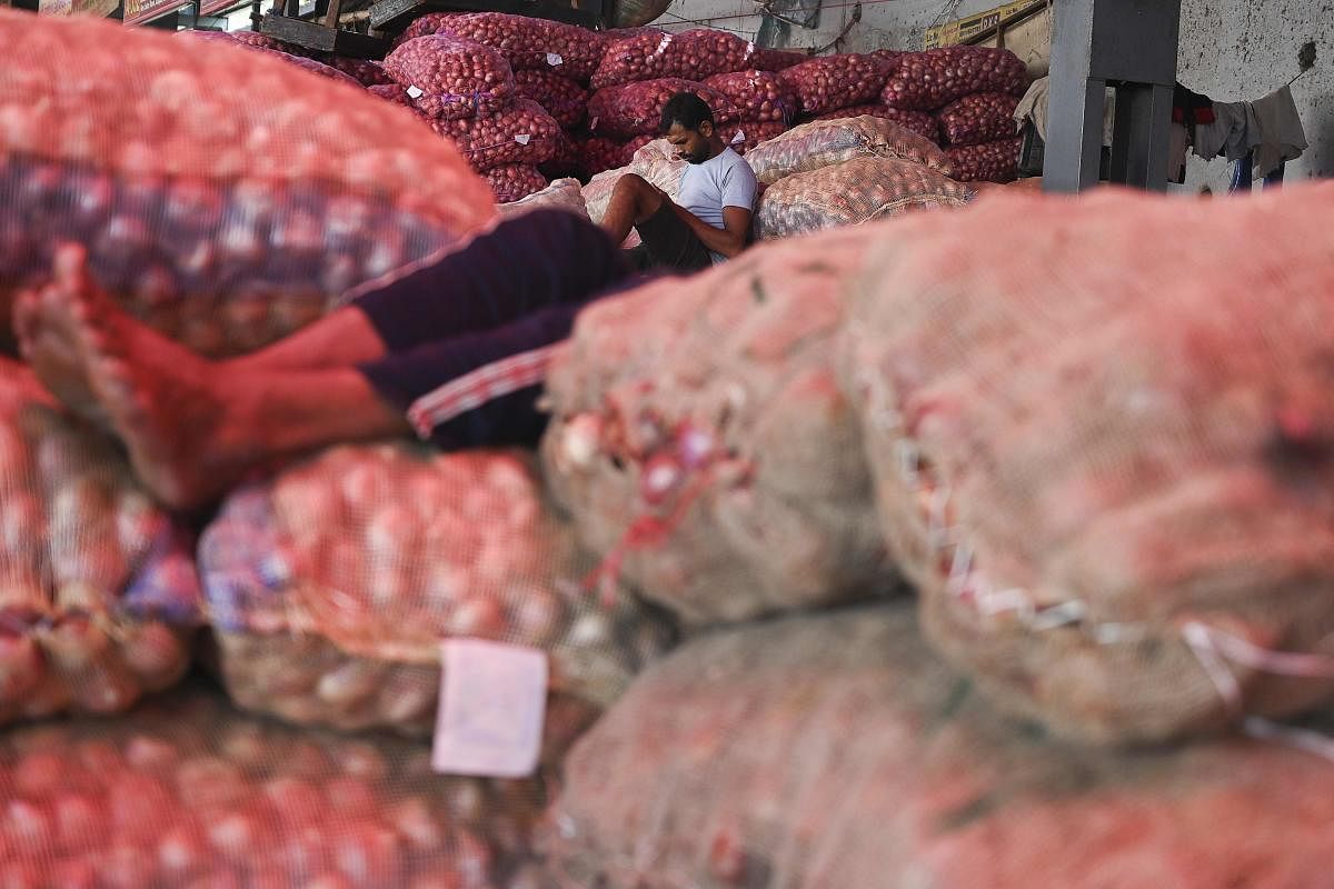 A worker sits on gunny bags filled with onions at a wholesale vegetable market in New Delhi on September 25, 2019. (AFP)