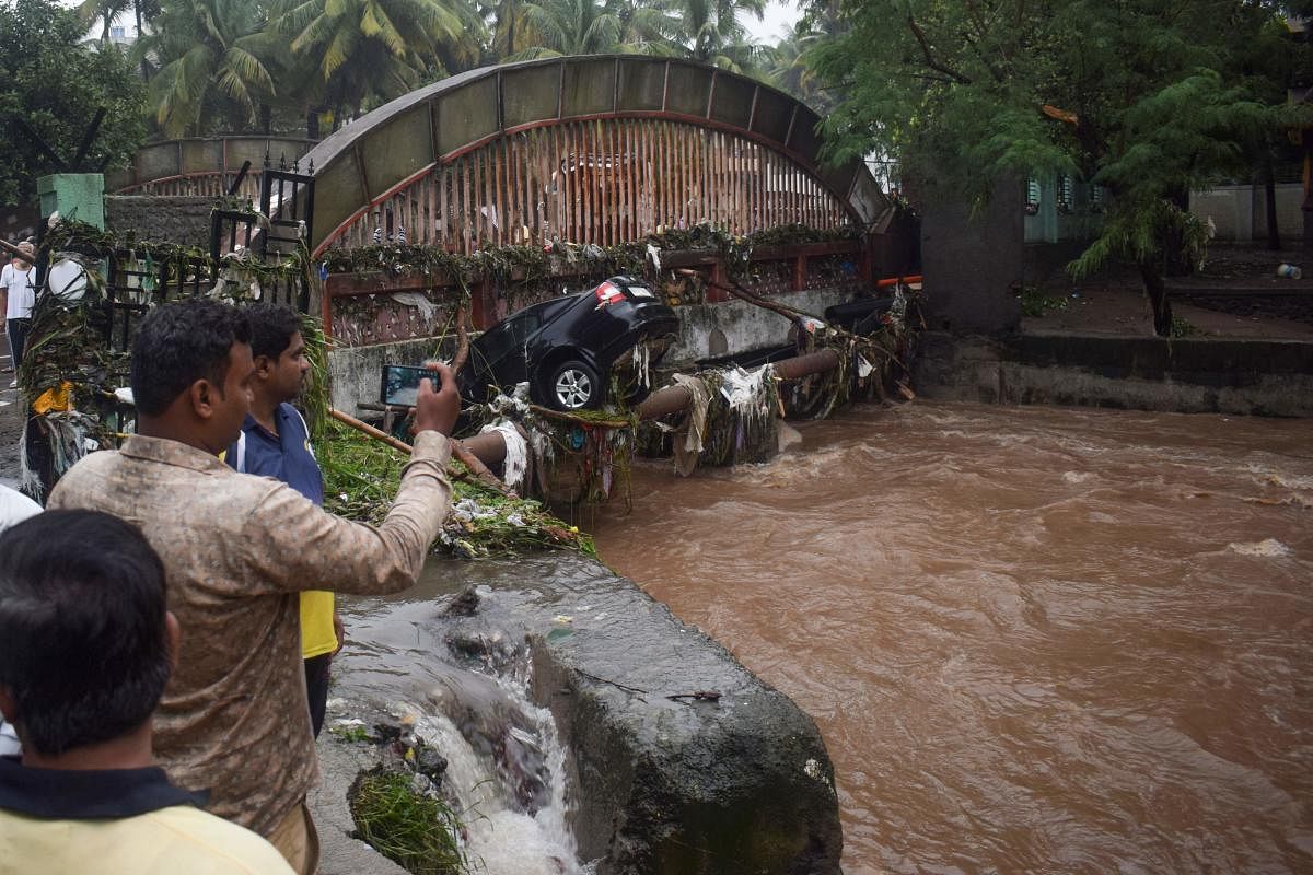 Onlookers and residents take photos of a car washed away by flash floods following heavy overnight rains in Pune on September 26, 2019. (AFP)
