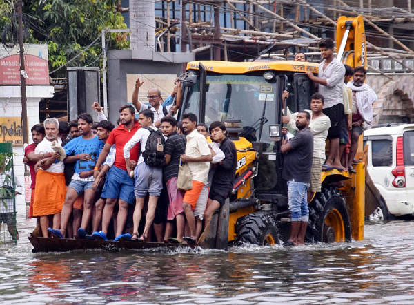 Patna: Residents ride a municipality earth-mover through a flooded street following heavy monsoon rain. (Photo/PTI)