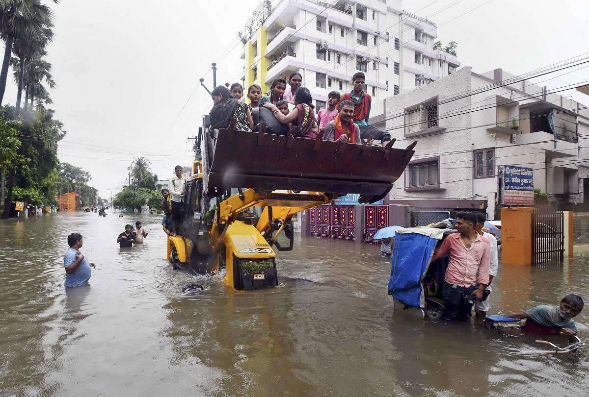  Patna Muncipal Corporation (PMC) officials in a JCB rescue to people from a water logged area after heavy rainfall in Patna. (PTI Photo)