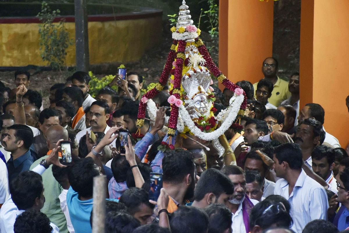 Devotees welcome the Karaga during procession in Madikeri on Sunday.