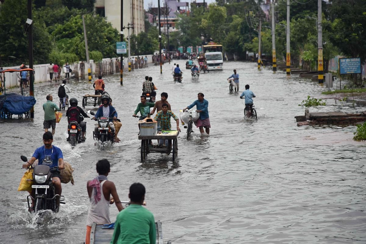 Commuters make their way on a waterlogged road following heavy rainfalls in Patna. (PTI Photo)