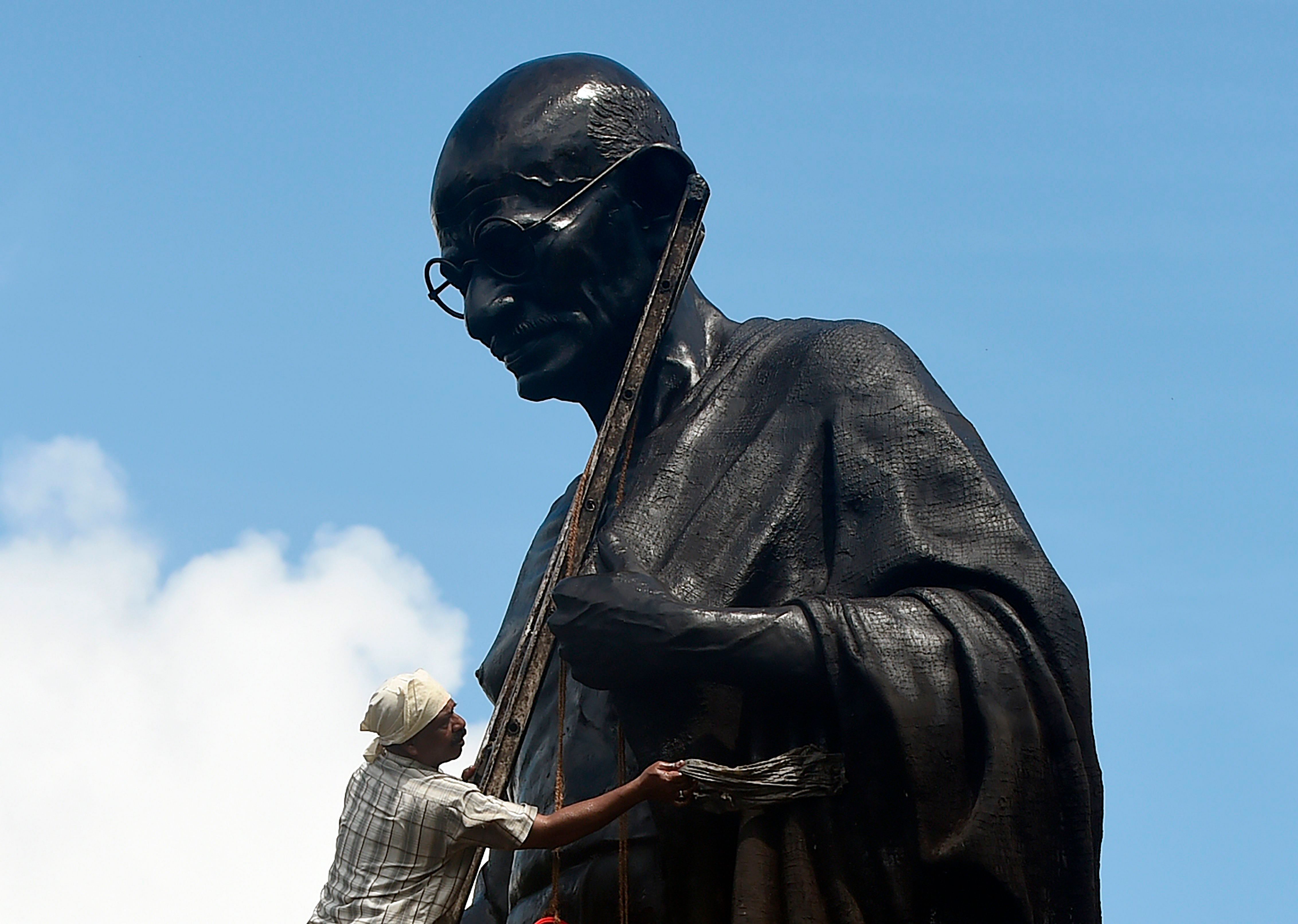 A worker cleans a statue of Mahatma Gandhi in Mumbai on October 1, 2019, ahead of Gandhi's 150th birth anniversary. (AFP Photo)