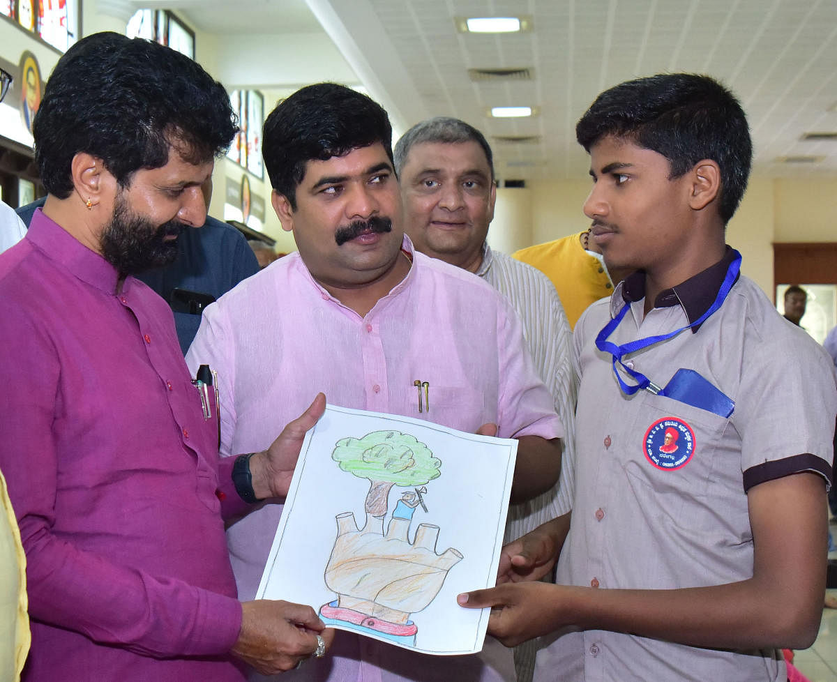 A student shows his drawing to Tourism Minister C T Ravi during an international convention of hearing and speech impaired at Sangha Nikethan in Mangaluru on Monday.
