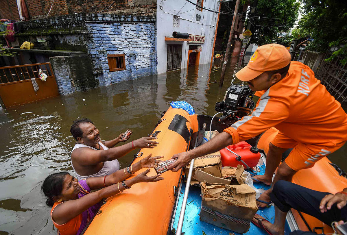 National Disaster Response Force (NDRF) workers distribute relife material to flood-affected people of Rajendra Nagar area after heavy rains, in Patna, Tuesday, Oct. 01, 2019. (PTI Photo)