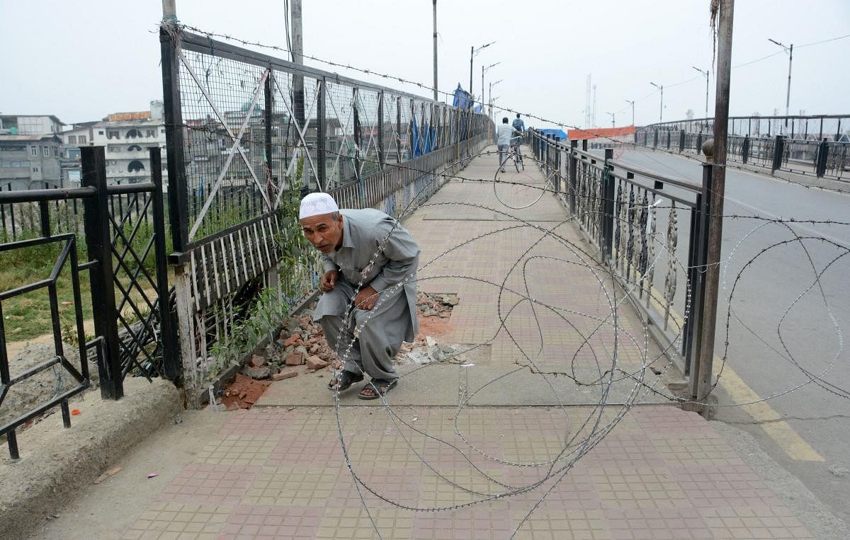 An elderly man attempts to cross through a blockade during restrictions after the abrogration of Article 370 and bifurcation of State, in Srinagar. (PTI Photo)