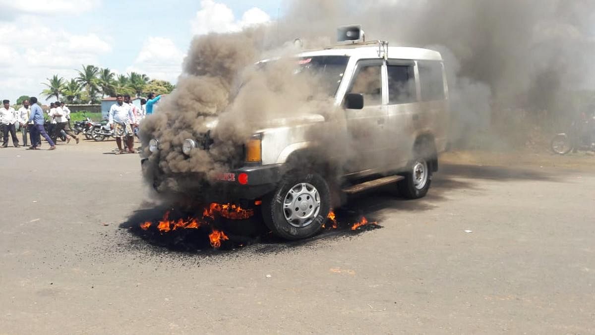 A group of locals set a police vehicle on fire following the collision between a tomtom and a government bus at Kolhar in Vijayapura district on Wednesday. DH PHOTO