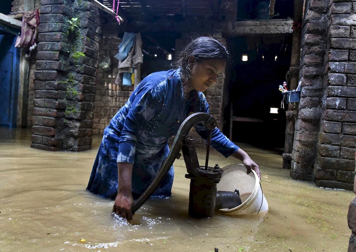 Patna: A young woman collects potable water from a handpump in a flooded area of Beldari Chak, in Patna. (PTI Photo)