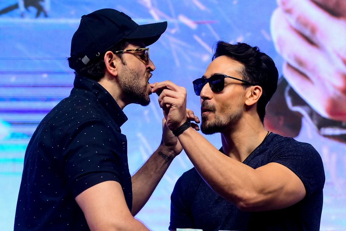 Bollywood actors Hrithik Roshan (L) and Tiger Shroff (R) interact with eachother during the promotion of their action thriller Hindi film 'War' in Mumbai on October 4, 2019. (AFP)