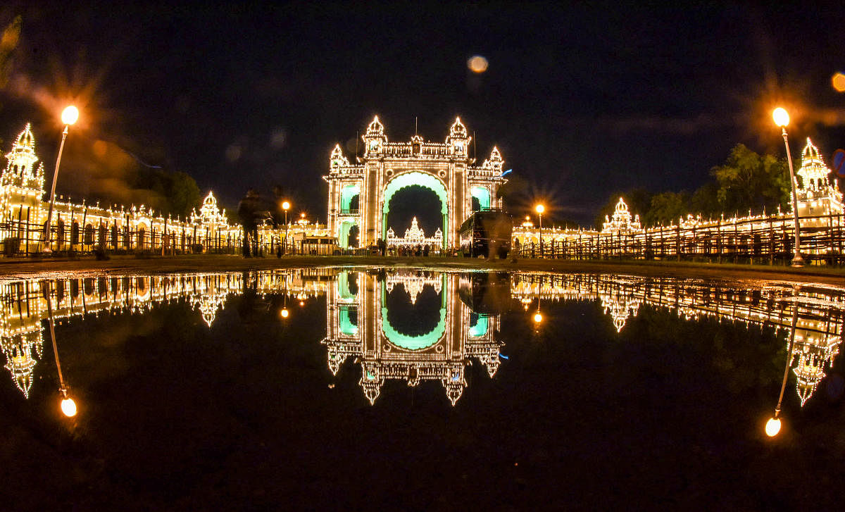 Reflection of the Mysuru Palace, from Jayamarthanda Gate, on the Exhibition Grounds side, all decked up for the Dasara celebration, in Mysuru, on Tuesday. It rained for some time on Tuesday evening. (DH Photo/B R Savitha)
