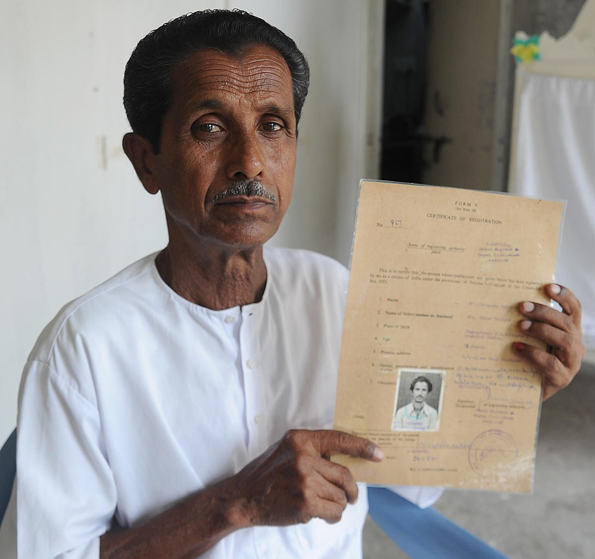 Nirepada Mallick (74) shows his citizenship certificate in RH-2 camp in Sindhanur. DH Photo/Pushkar V