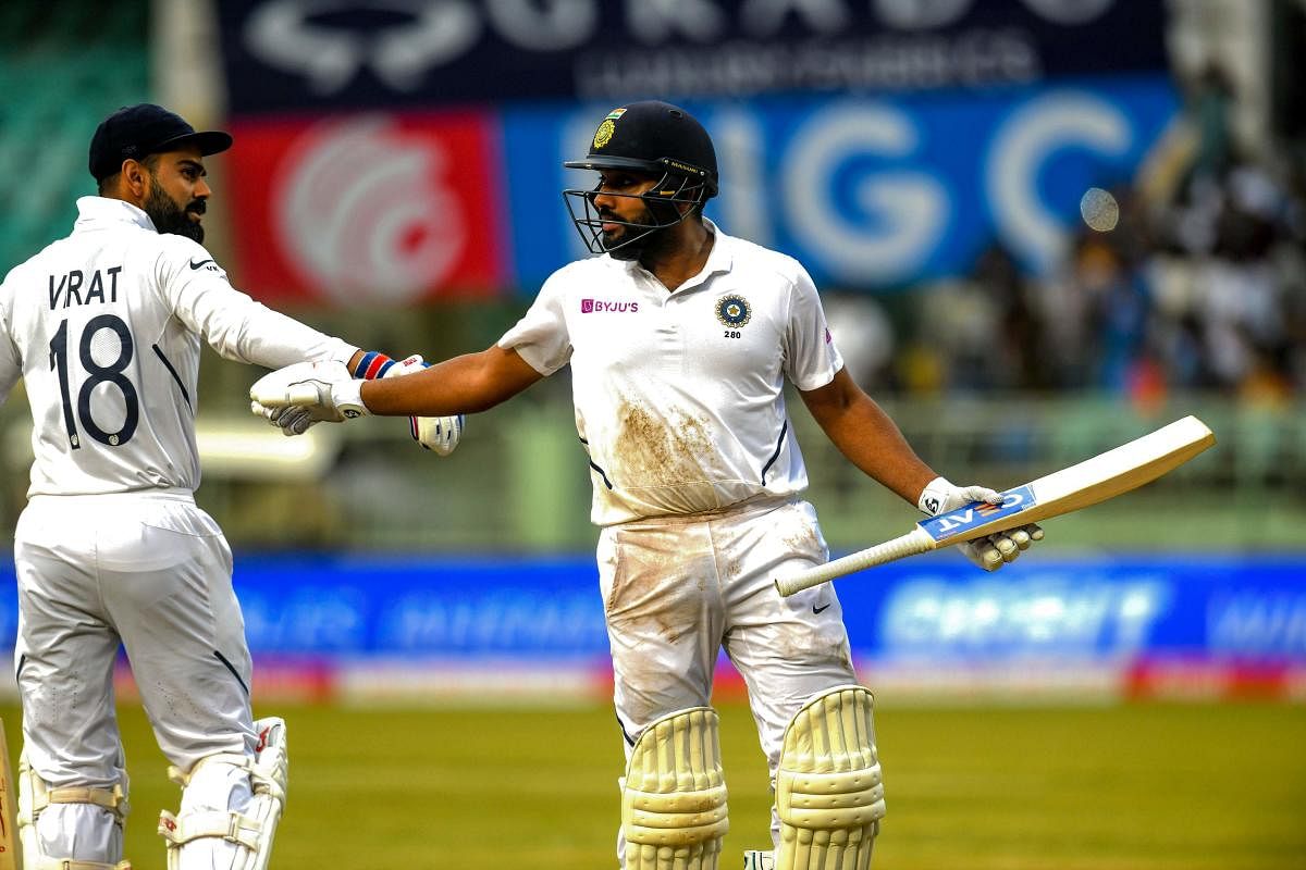 India's captain Virat Kohli (L) congratulates his teammate Rohit Sharma (R) as he leaves the pavillion during the fourth day's play of the first Test match between India and South Africa at the Dr. Y.S. Rajasekhara Reddy ACA-VDCA Cricket Stadium in Visakh