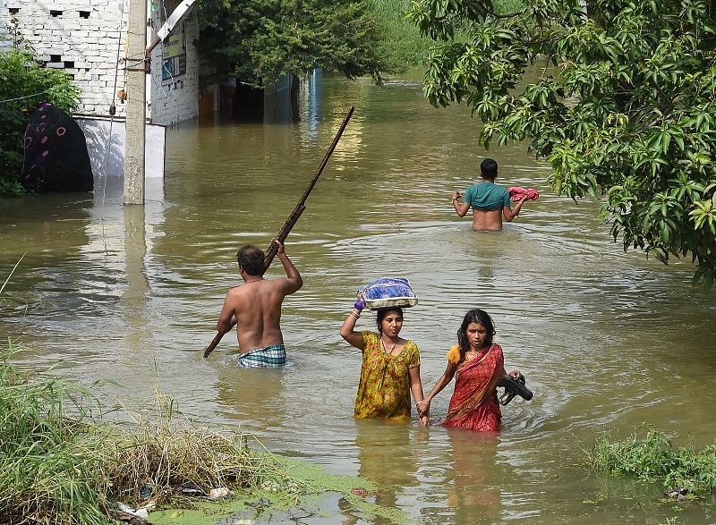 Villagers wade across a locality flooded by the Punpun river, in Patna. (PTI Photo)