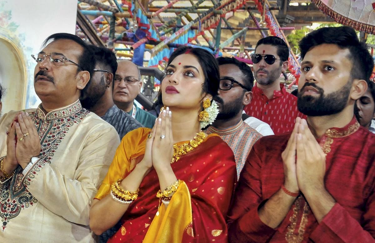 Noted film actress and Trinamool Congress MP Nusrat Jahan and her husband Nikhil Jain(R) participate in 'Pushpanjali' offering rituals of 'Maha Ashtami' during the ongoing Durga Puja festival, in Kolkata onSunday. West Bengal Minister Arup Biswas is also seen. (PTI Photo)