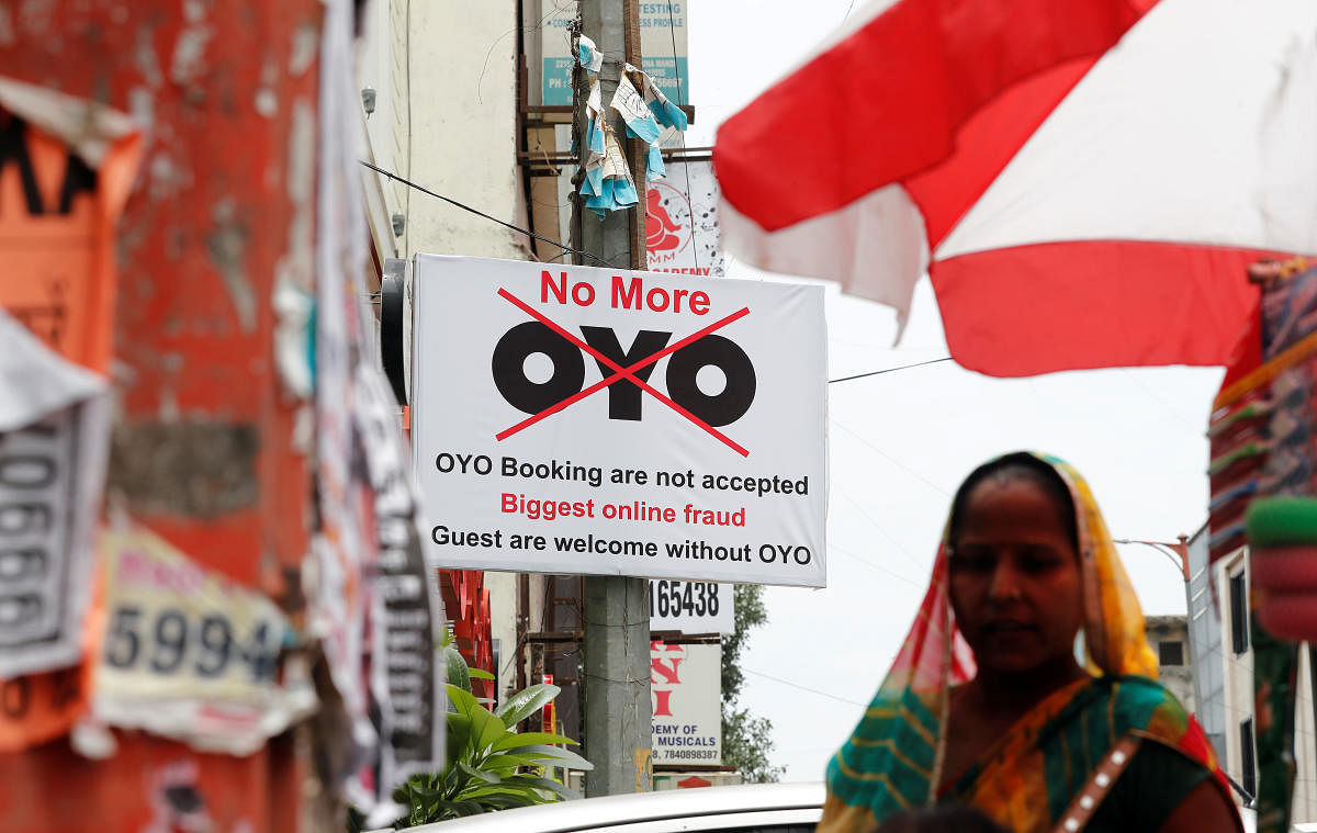A woman walks pasts a sign against Oyo, placed outside a hotel in New Delhi. (Photo by Reuters)