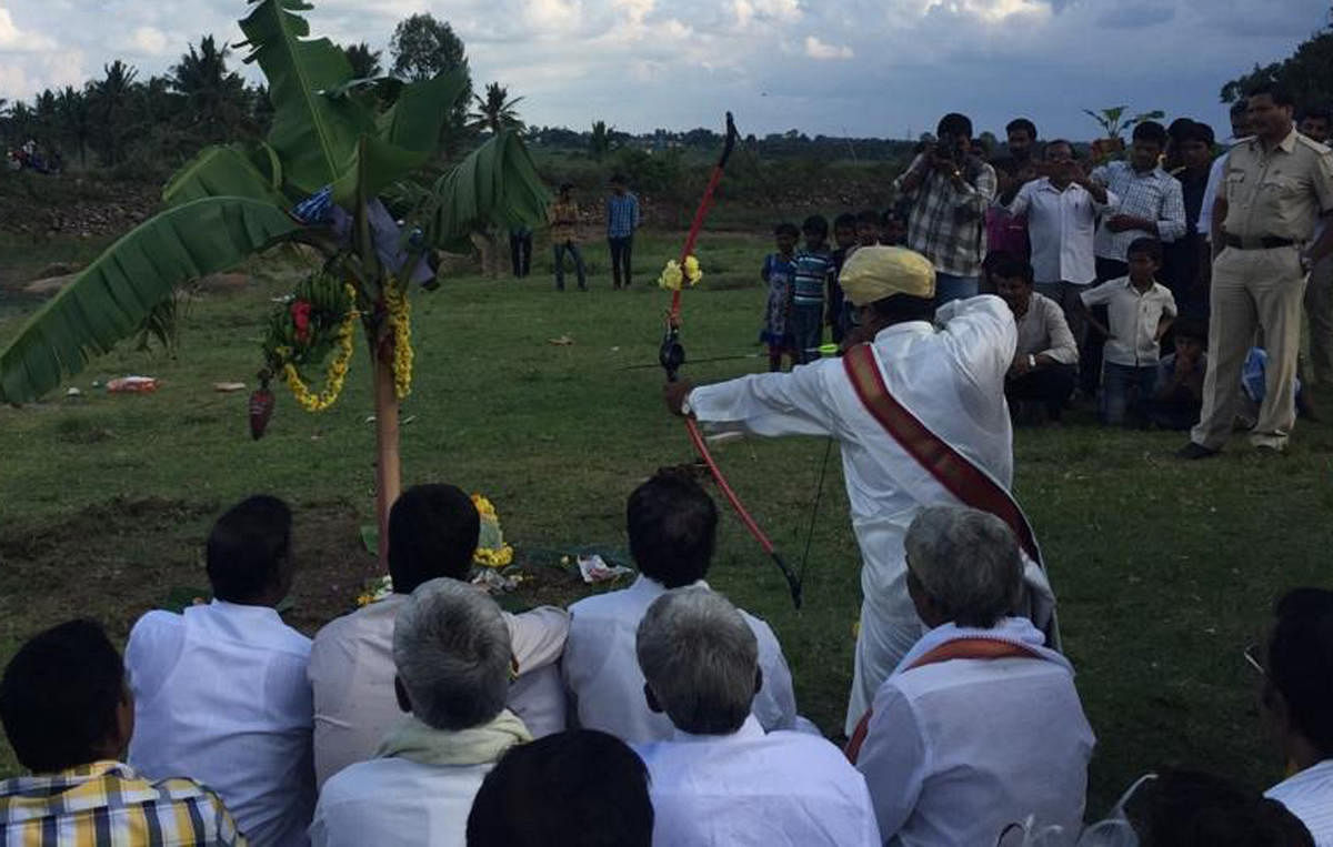 The head of Patela community, A M Mahesh, hitting an arrow at a bunch of bananas to mark Vijayadashami celebrations at Aradavalli in Chikkamagaluru taluk on Tuesday.
