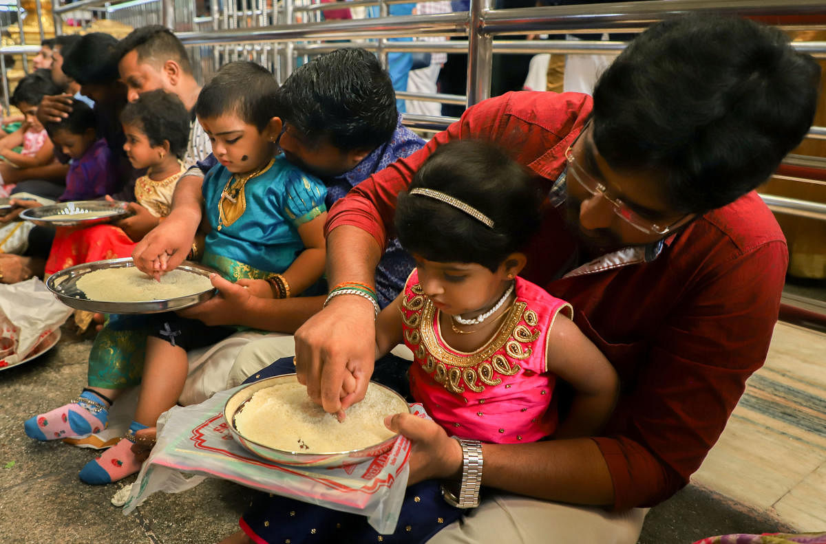 Parents initiate their children into world of learning and writing on the occasion of Vijayadashami. (PTI Photo)