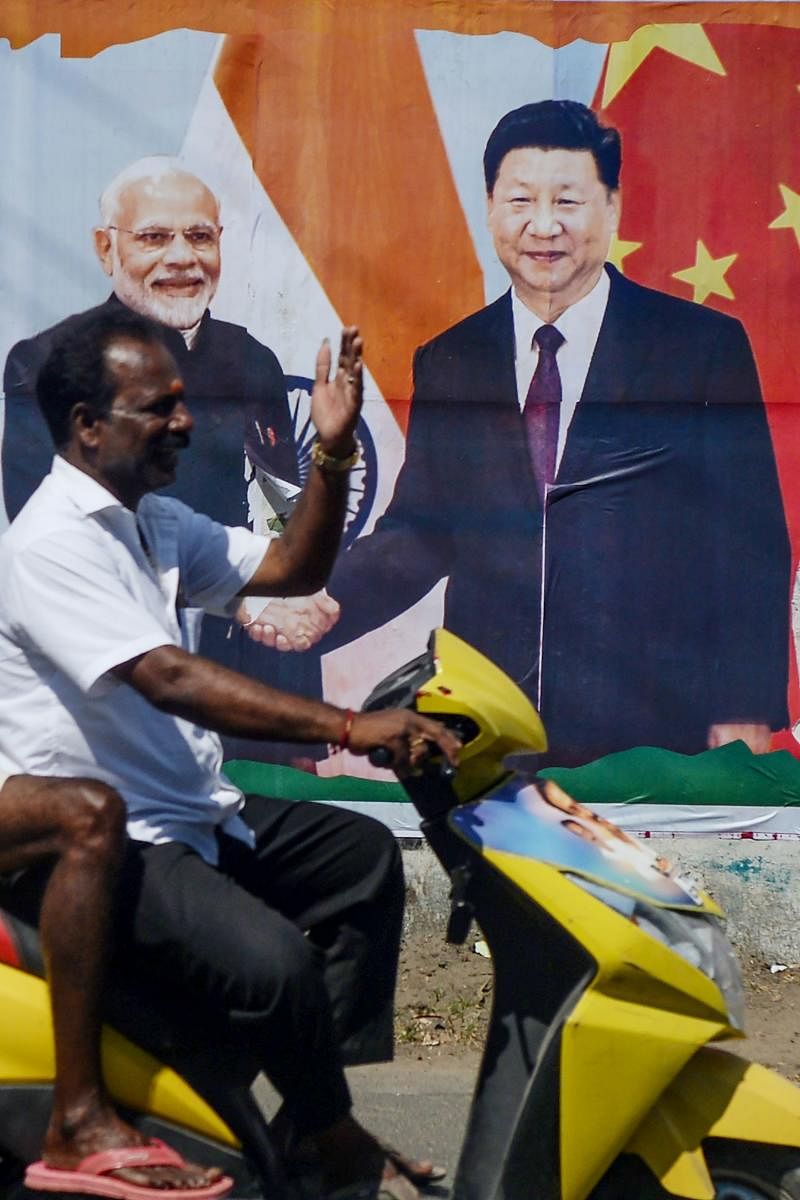 A motorist drives past a poster welcoming China's President Xi Jinping (R) in Chennai on October 11, 2019, ahead of a summit with his Indian counterpart Prime Minister Narendra Modi. (AFP)