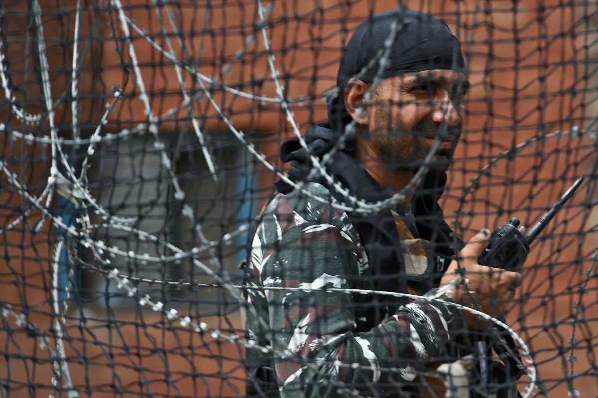 A security personnel stands guard on a street in Srinagar (Photo by AFP)