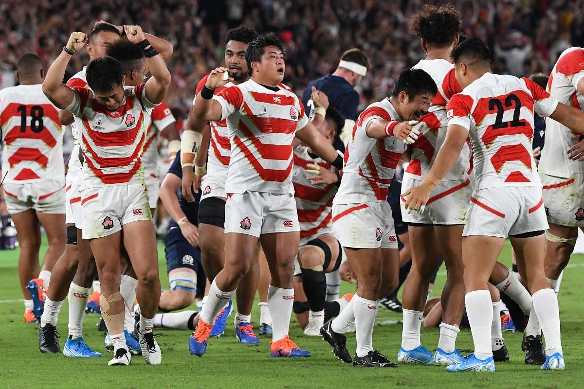 Japan's wing Kenki Fukuoka (L) celebrates with teammates after winning the Japan 2019 Rugby World Cup Pool A match between Japan and Scotland at the International Stadium Yokohama in Yokohama on October 13, 2019. (Photo by William WEST / AFP)