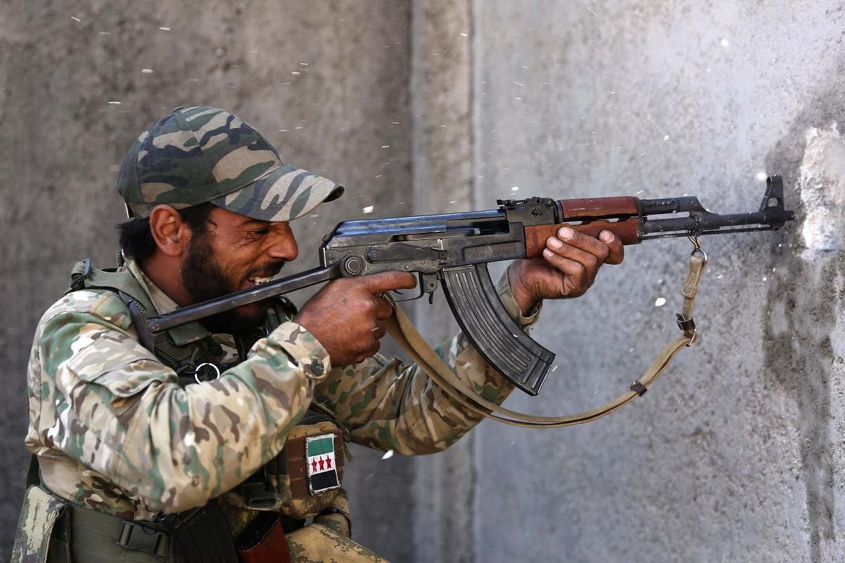 A Turkish-backed Syrian fighter grimaces as he fires his rifle on enemy positions, in Syria's northeastern town of Ras al-Ain in the Hasakeh province along the Turkish border as Turkey and its allies continue their assault on Kurdish-held border towns in