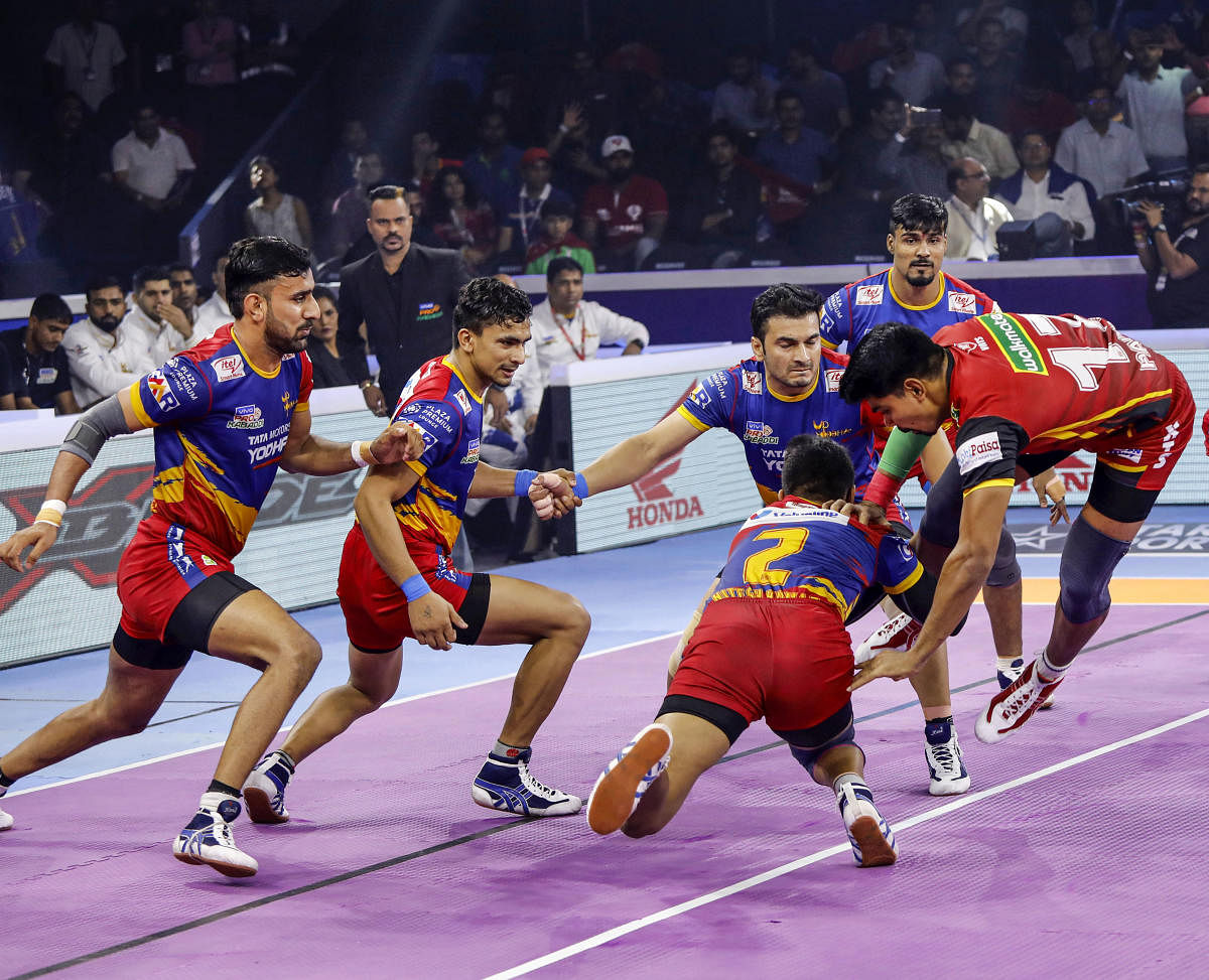 Bengaluru Bulls’ Pawan Sehrawat (right) jumps past the UP Yoddha players for a successful raid during the Eliminator 1 in Ahmedabad on Monday. 