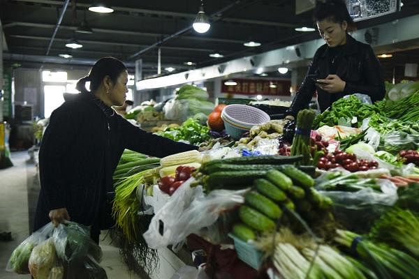 A customer (L) shops for vegetables at a market in Beijing on October 15, 2019. (AFP photo)