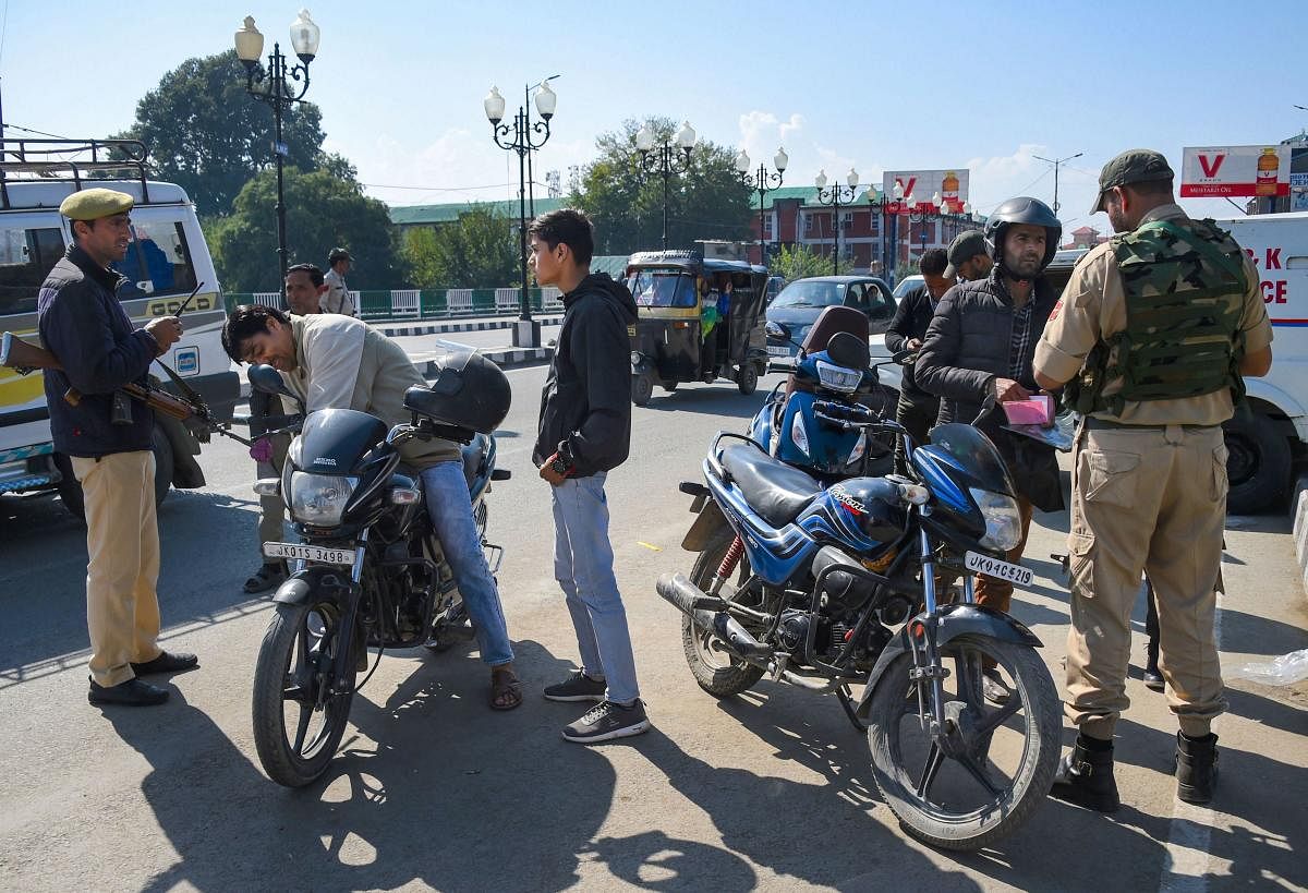 Security personnel check documents of of motorcyclists at a road, during a shut down in Srinagar. (PTI Photo)