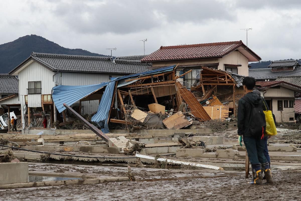A man looks at flood-damaged homes in Nagano after Typhoon Hagibis hit Japan on October 12 unleashing high winds, torrential rain and triggered landslides and catastrophic flooding. (Photo by AFP)