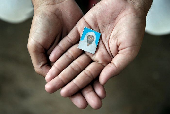 Irshad Khan, 24, holds a picture of his late father Pehlu, 55, in Jaisinghpur. (Reuters photo)