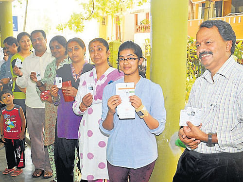 Voters flash their ID cards, at Mahajana School, in Mysore. DH Photo