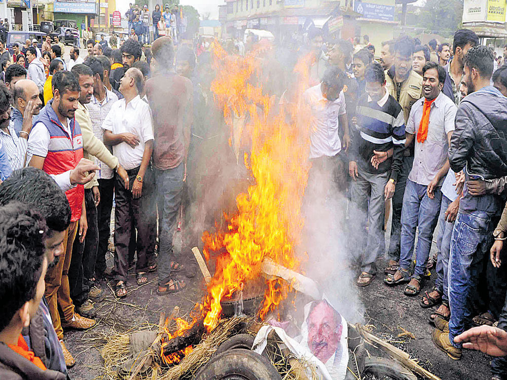 Protesters burn tyres and pictures of minister K J George at General K S&#8200;Thimmaiah Circle in Madikeri on Thursday.