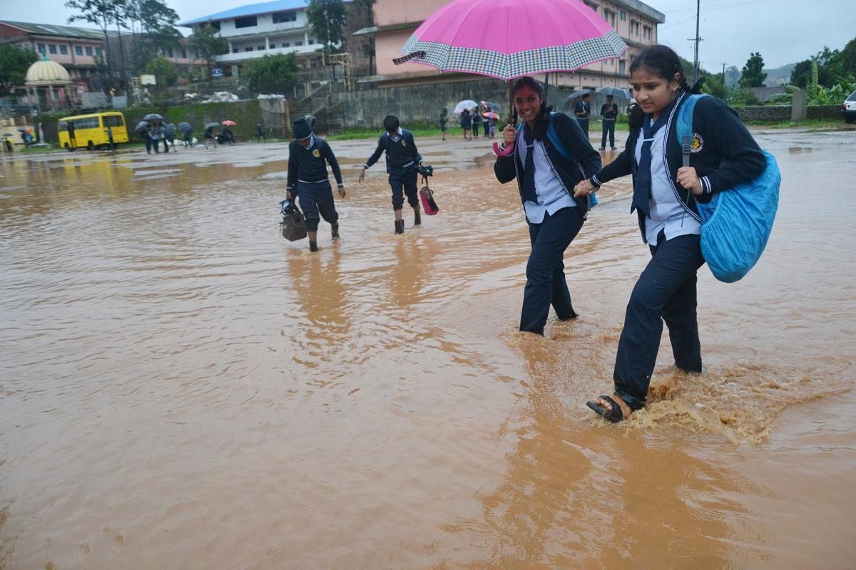Students wade through the inundated Gandhi Maidan in Madikeri on Wednesday. (Right) The Chelyadka bridge on Puttur-Panaje Road in Dakshina Kannada district has been submerged owing to heavy rain. dh PhotoS
